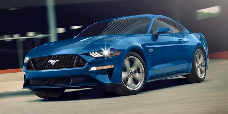 A blue 2023 Ford Mustang driving at night.