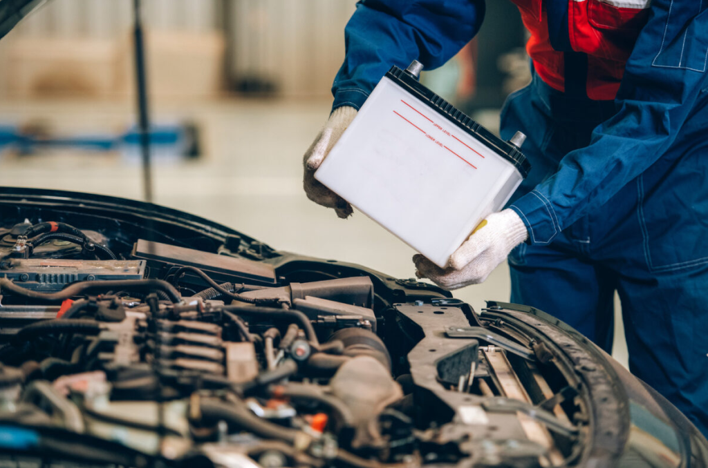 A vehicle techinician installing a new car battery.